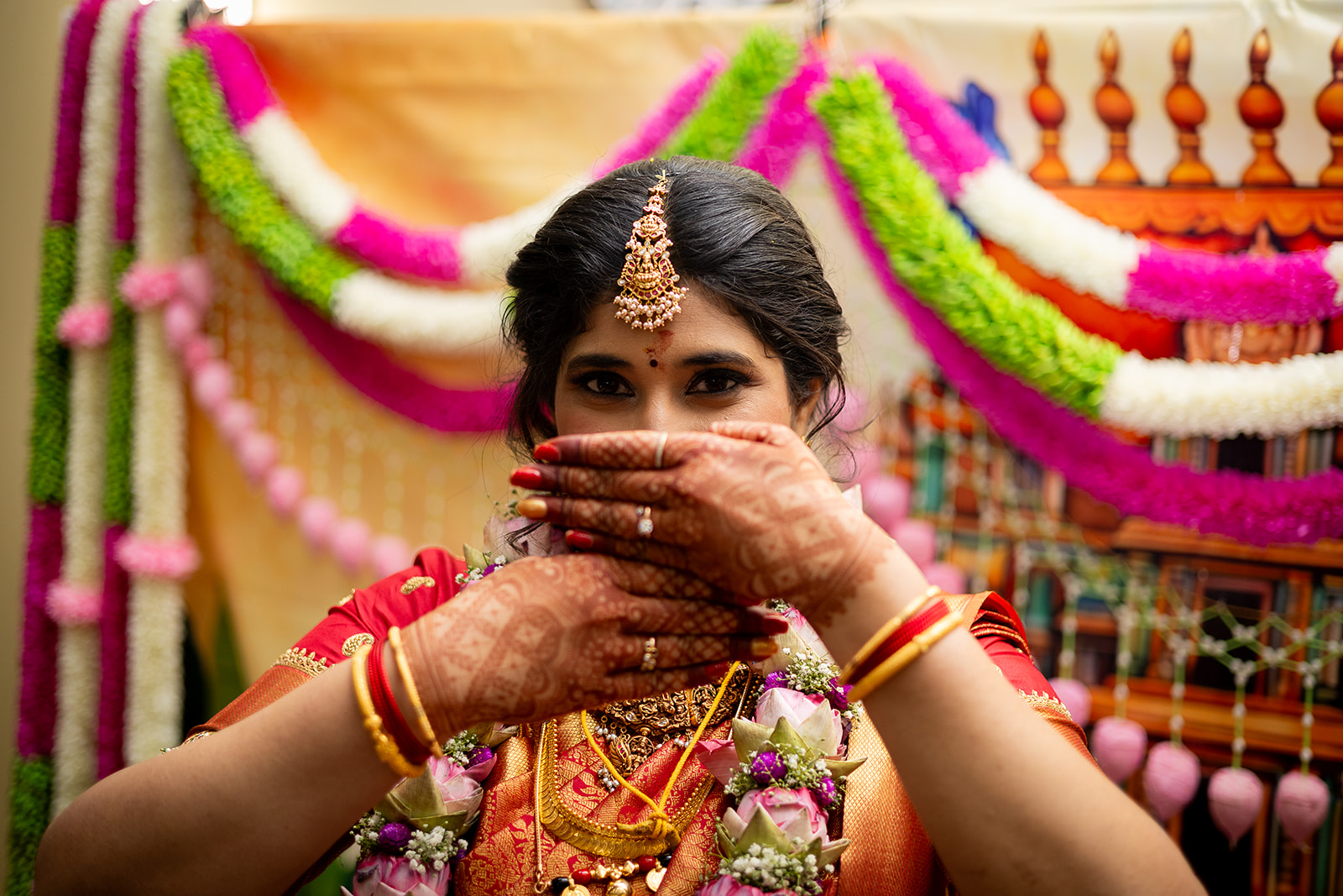 A bride with intricate mehndi holding flowers near her face