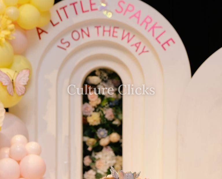 A Little Sparkle Is On The Way arch with florals and a pastel balloon garland