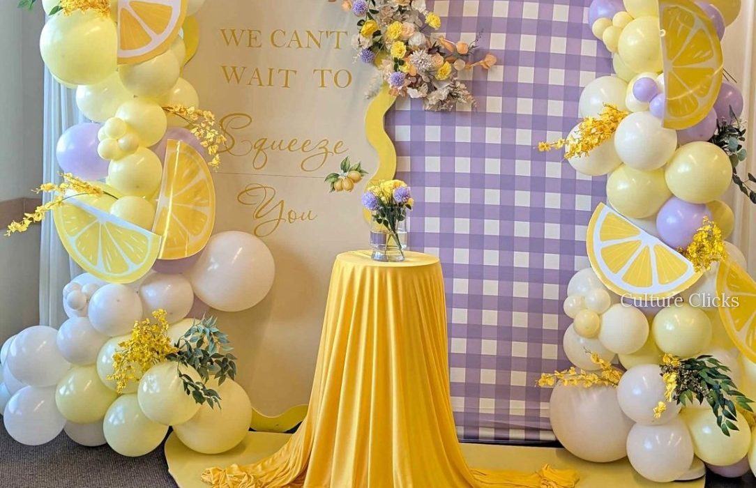 Lemon and lavender gingham backdrop with yellow balloon garlands and lemon slices
