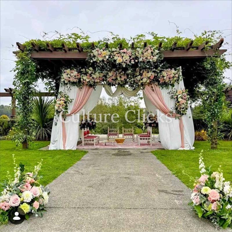 Outdoor mandap with a blush and ivory floral canopy and draped columns