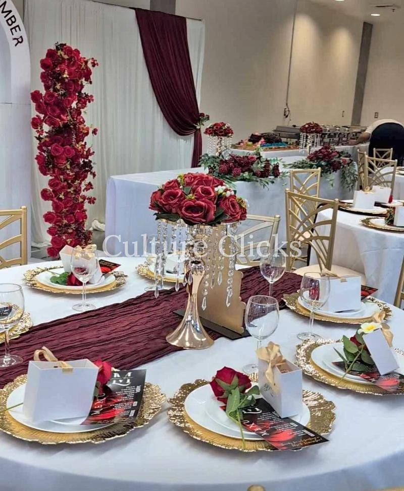 Reception table with red roses, gold chargers and burgundy linens