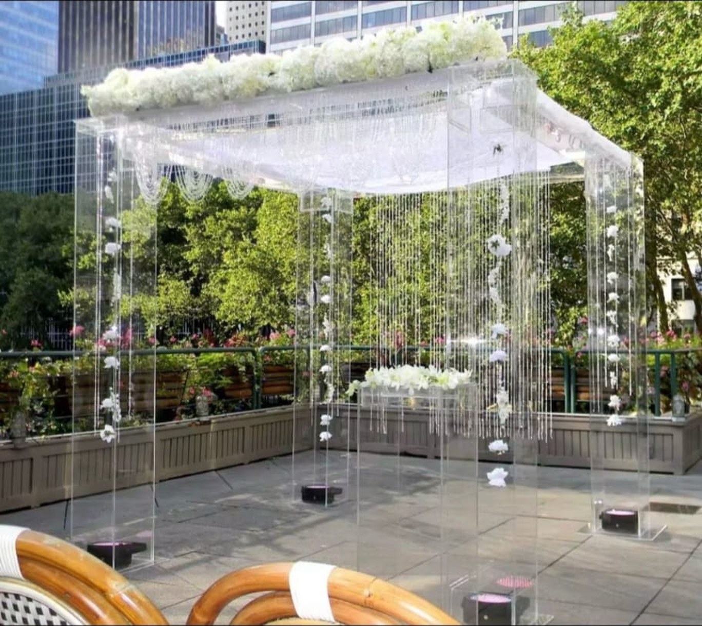 Clear acrylic mandap with white flowers on top and hanging crystal strands on an outdoor terrace