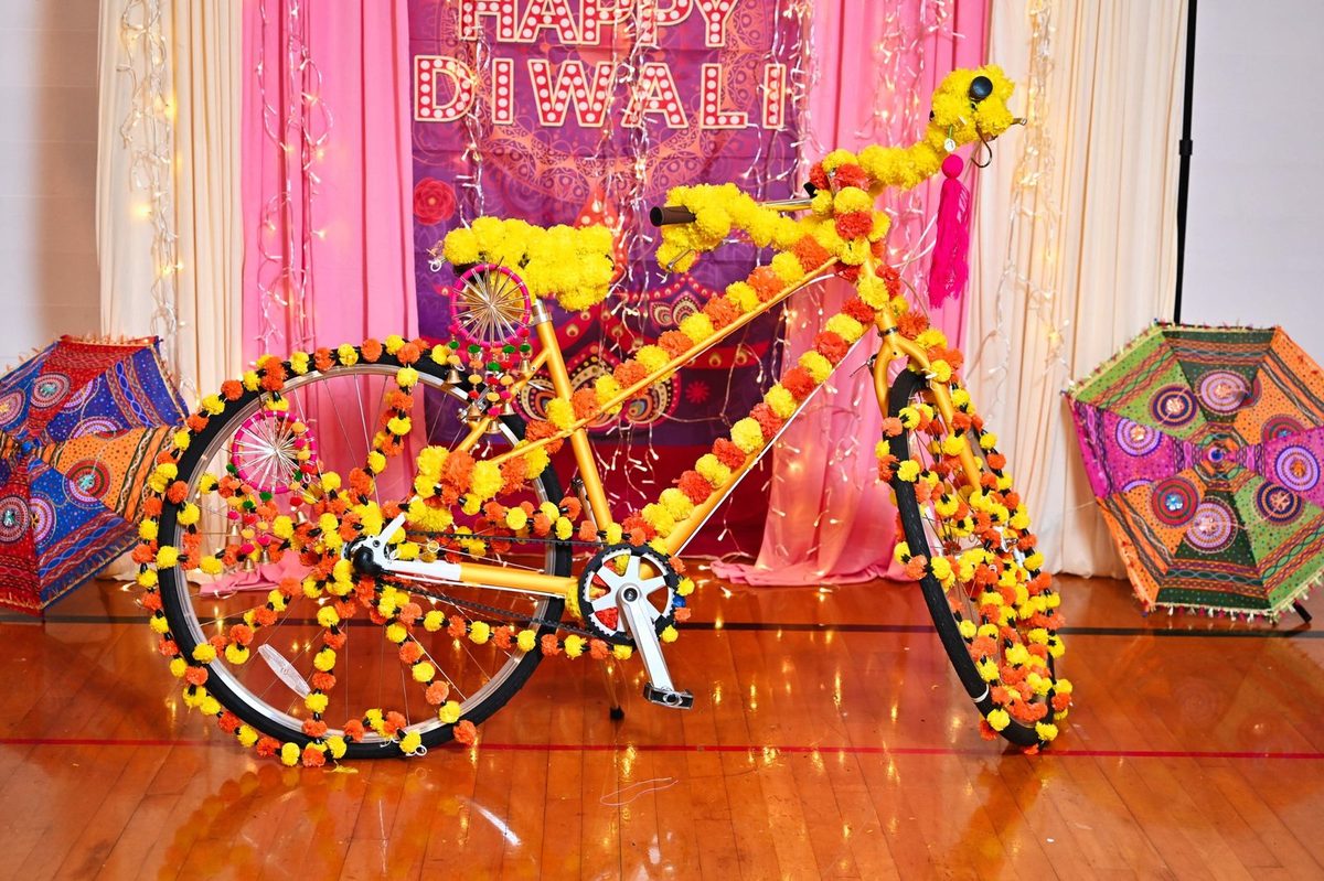 Bicycle covered in marigold garlands in front of a Happy Diwali backdrop