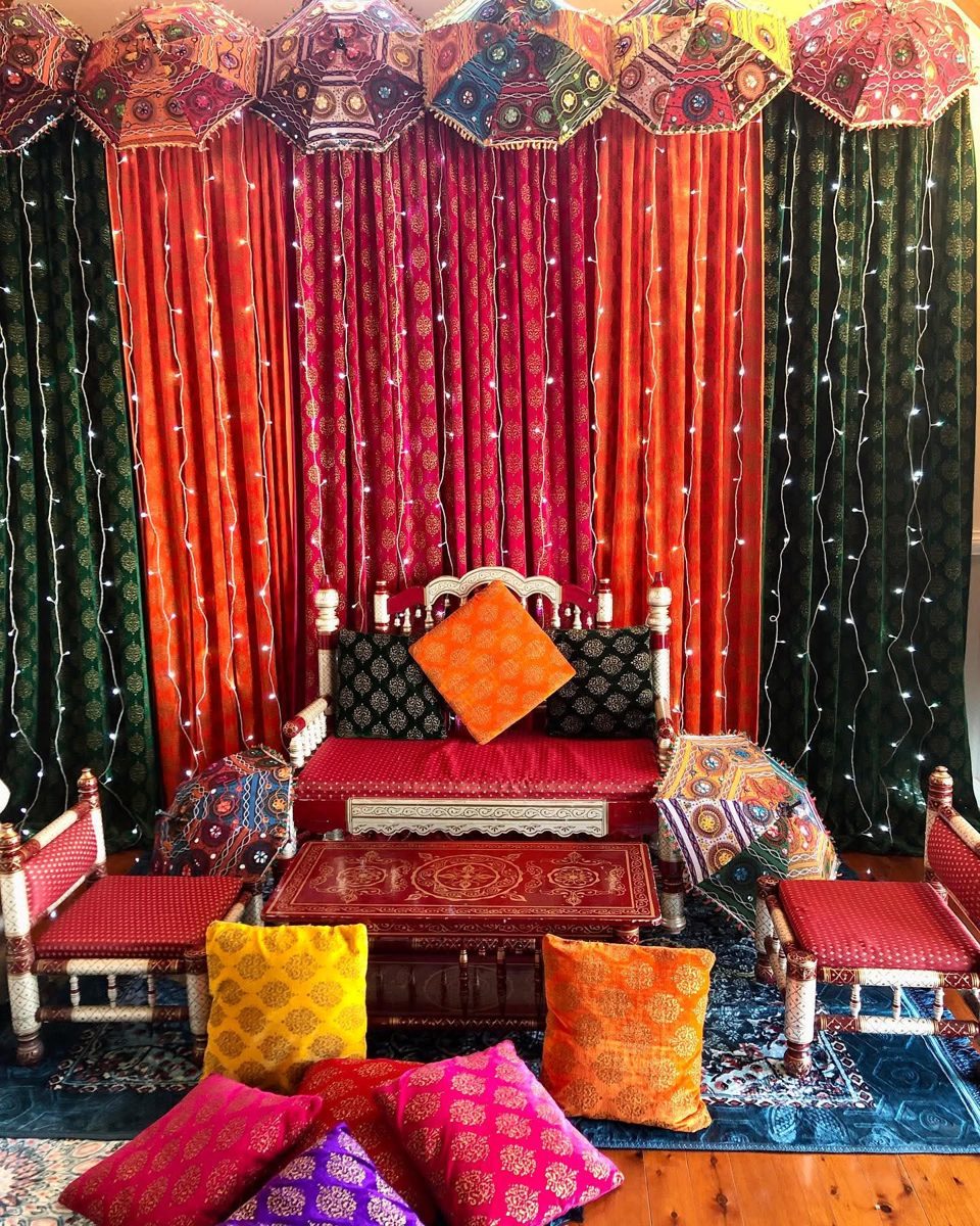 Colourful embroidered umbrellas over red, orange and green drapes with traditional seating