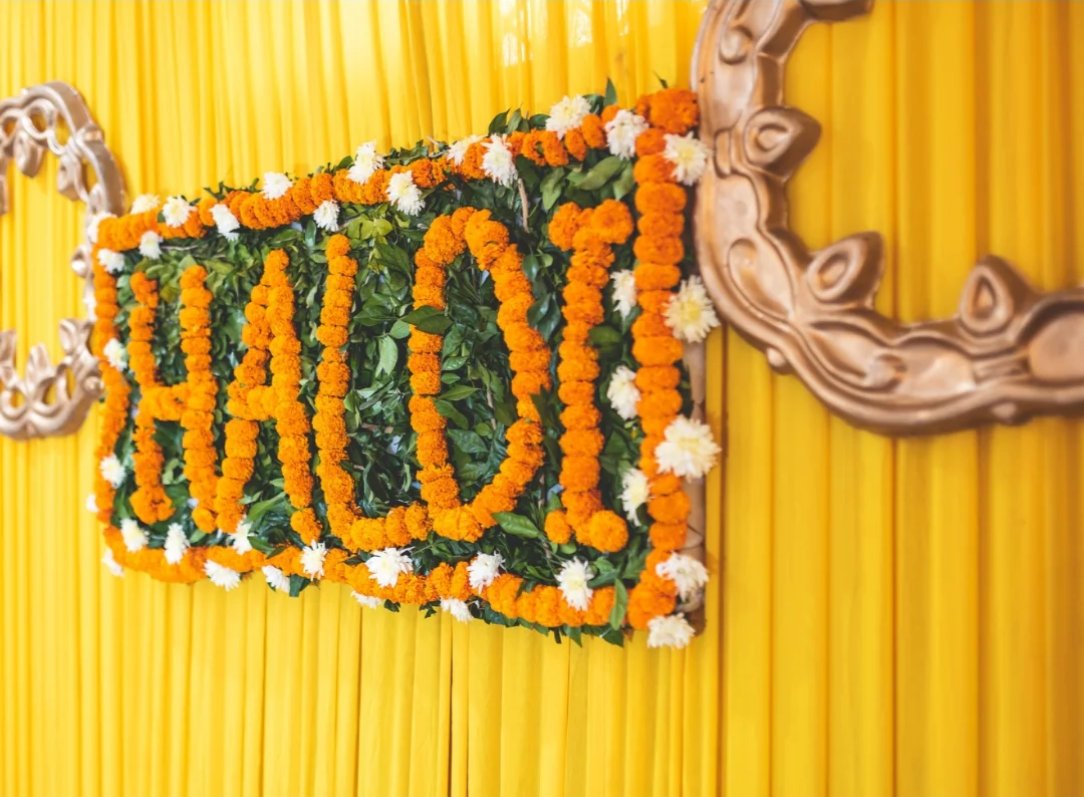 HALDI lettering made of marigolds on a yellow draped wall