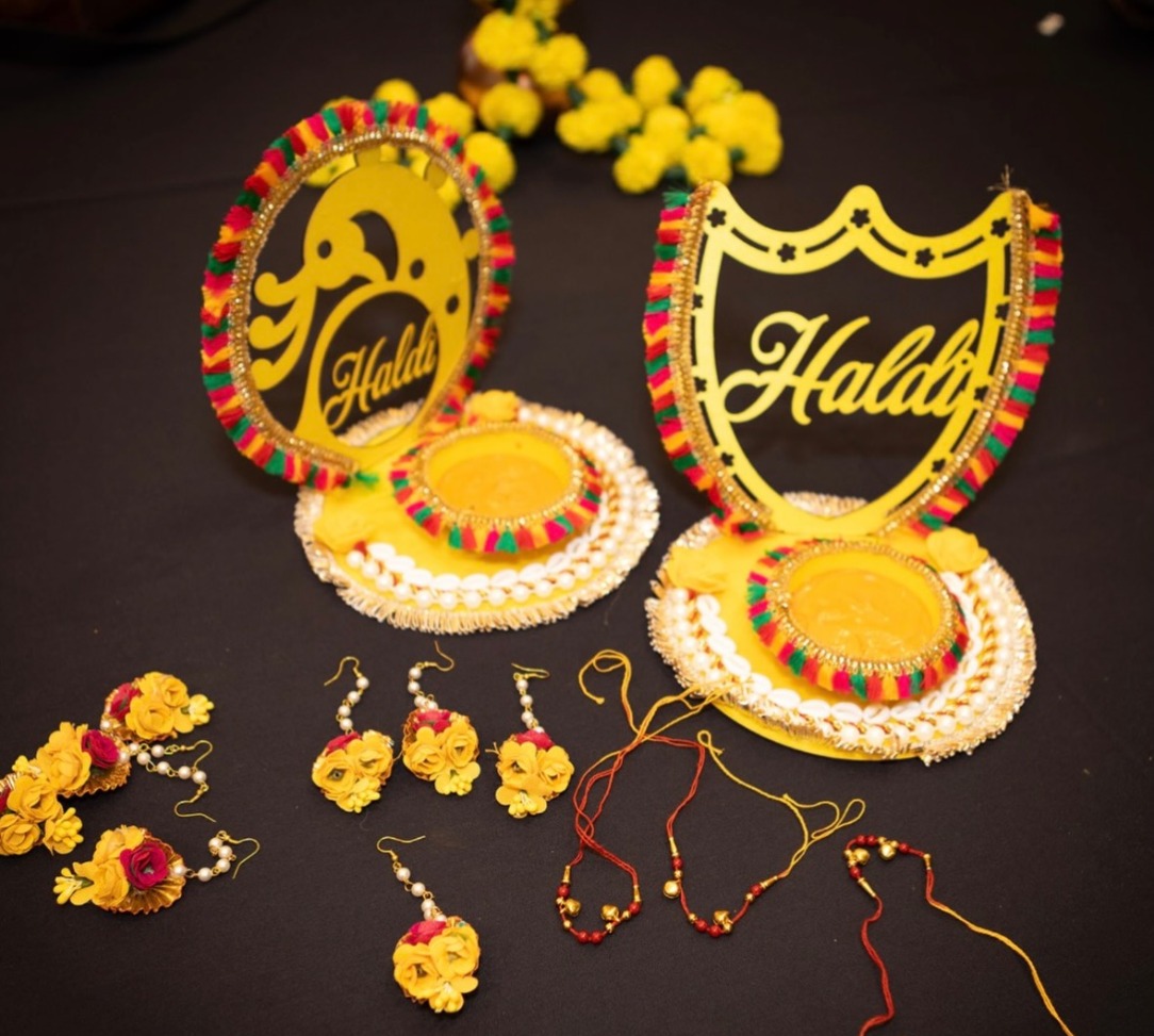 Haldi decor plates with yellow Haldi lettering, marigold flowers and floral jewelry