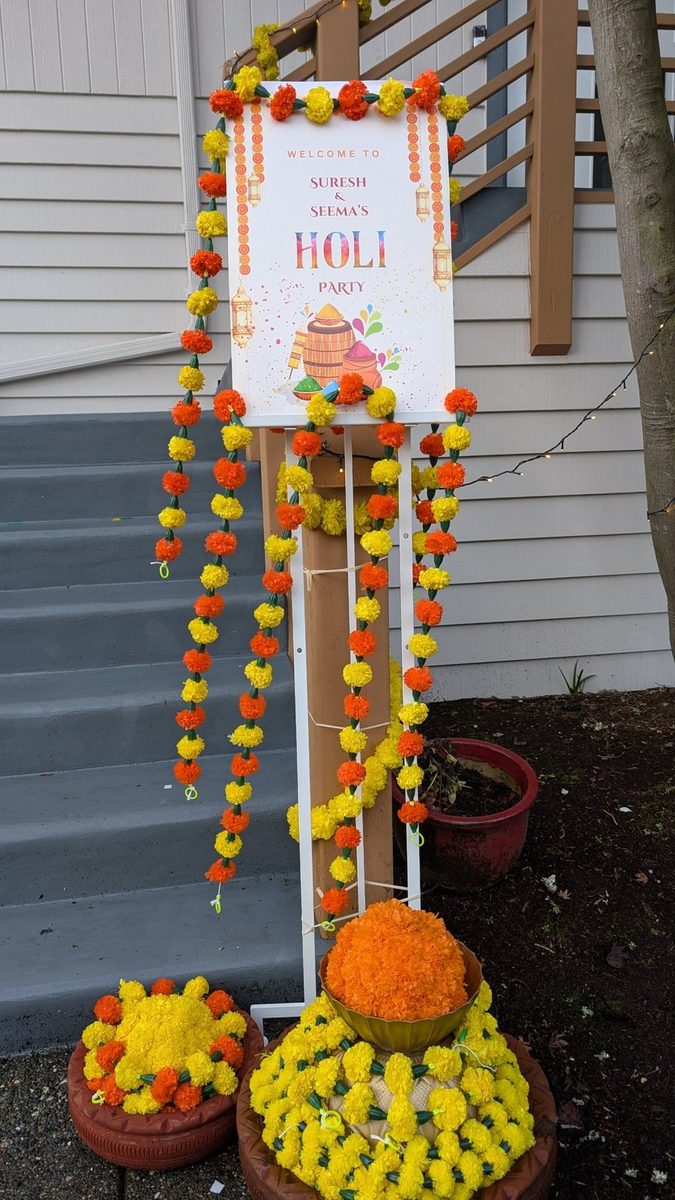 Welcome sign framed with marigold garlands and marigold flower pots at a home entrance