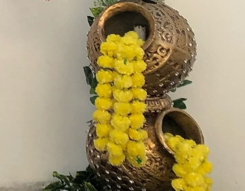 Stacked brass pots with yellow marigold garlands spilling out