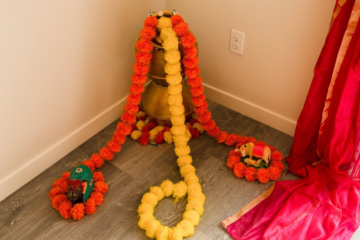 Marigold garlands around a brass pot with decorative elephant and cow figurines