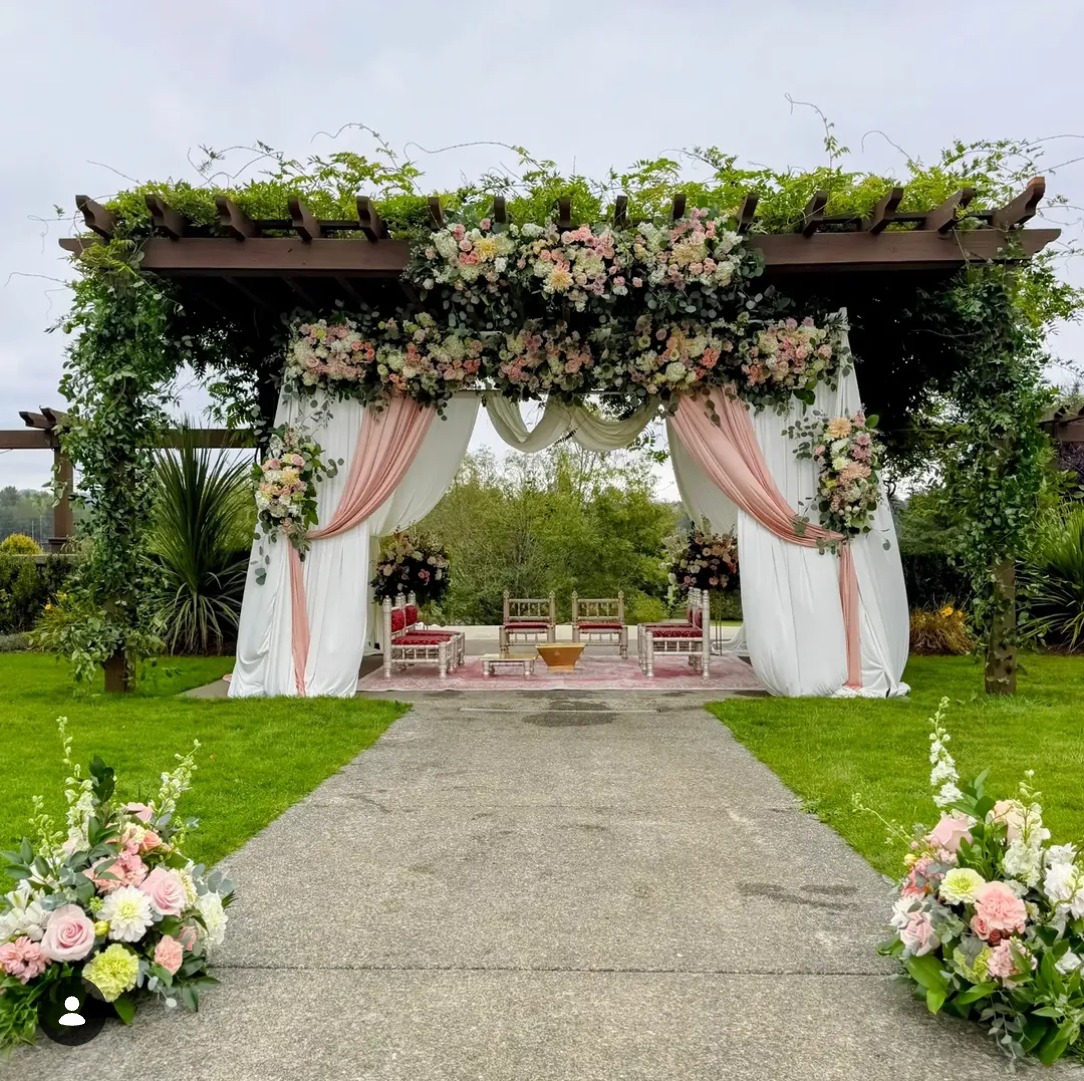 Outdoor pergola mandap with white and blush drapes and fresh floral arrangements at Lord Hill Farms