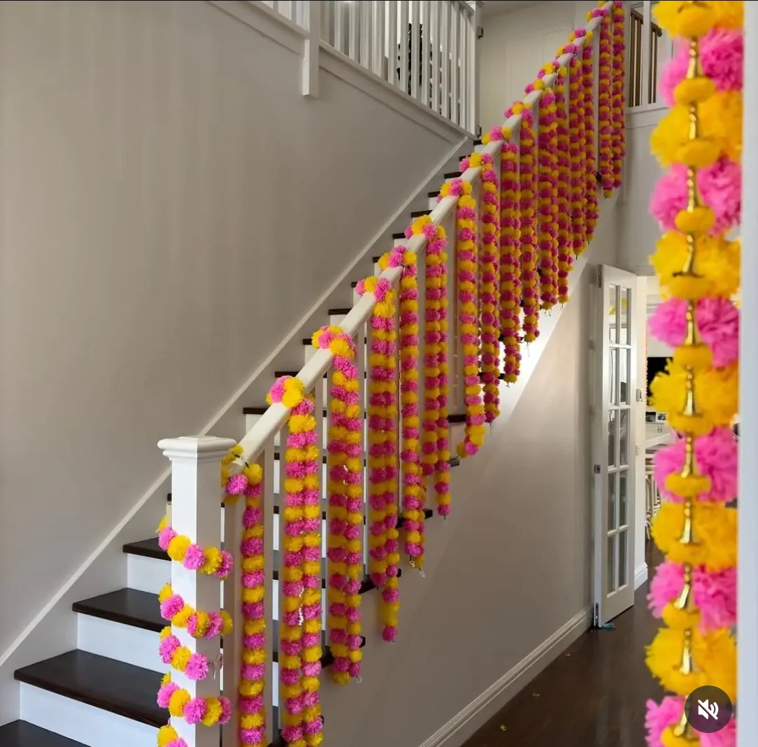 Staircase railing decorated with pink and yellow marigold garlands