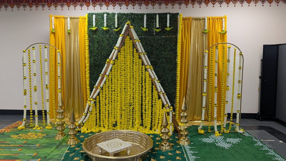 Yellow drapes, green hedge wall and a marigold triangle frame with gold tub and lamps